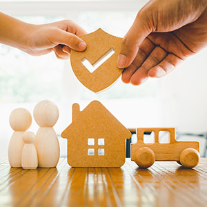 2 hands holding a shield above a family, home, and car