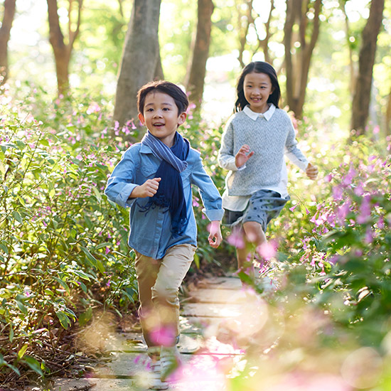 Two smiling children running down a path