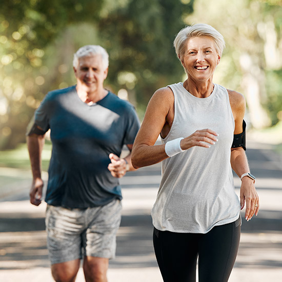 An older couple smiling while jogging